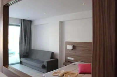 a bedroom with a chair and a mirror at Fedrania Gardens Hotel in Ayia Napa