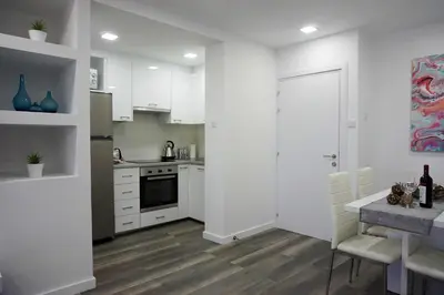 a kitchen with white cabinets and a table with chairs at Lazuli Sea View Beachfront Ap 43 in Larnaka