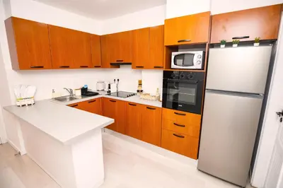 a kitchen with wooden cabinets and a refrigerator at Lazuli Sea View Beachfront Ap 21 in Larnaka