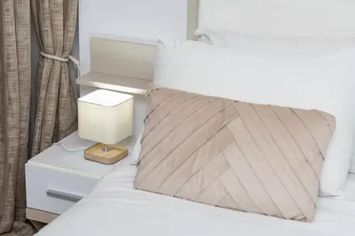 a bedroom with a bed with a nightstand and a white bedspread at Lazuli Beach & Pool Apartment 501 in Larnaka