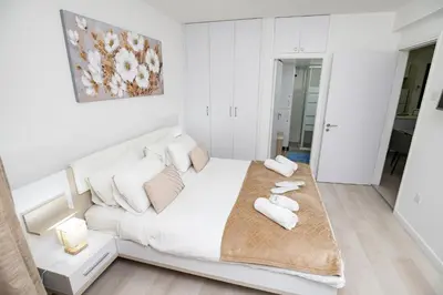 a white bedroom with a large white bed with towels on it at Lazuli Beach & Pool Apartment 501 in Larnaka