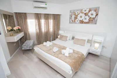 a bedroom with a large white bed and a desk at Lazuli Beach & Pool Apartment 501 in Larnaka