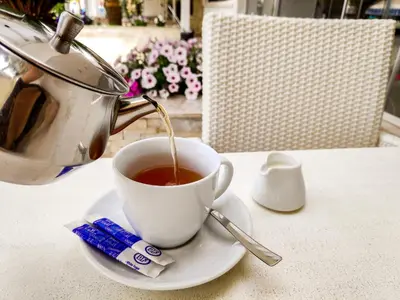 a teapot pouring tea into a cup on a table at Senator Hotel Apartments - Adults Only in Ayia Napa