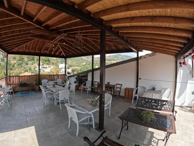 a patio with white chairs and tables and a wooden ceiling at AgroSpito Traditional Guest House in Agros