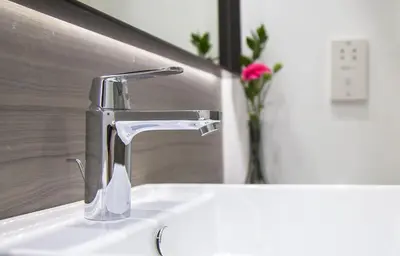 a bathroom sink with a faucet and a vase with a rose at Crystal Springs Beach Hotel in Protaras
