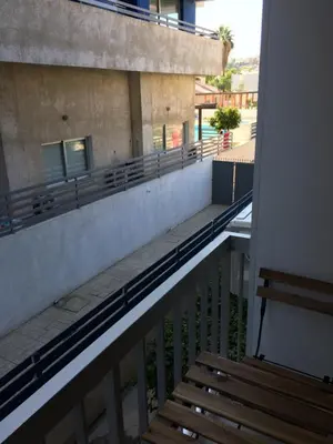 a balcony with a wooden bench and a building at Billis Beach Apartment in Limassol