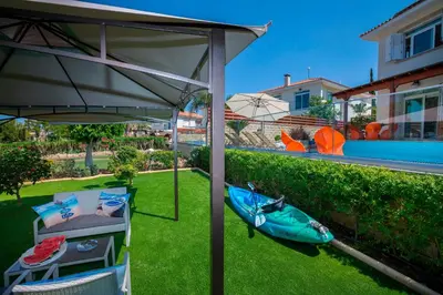a patio with a kayak on the grass next to a house at Villa Ricky in Protaras