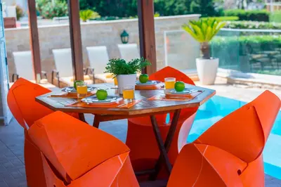 a table with orange chairs and a table with food on it at Villa Ricky in Protaras