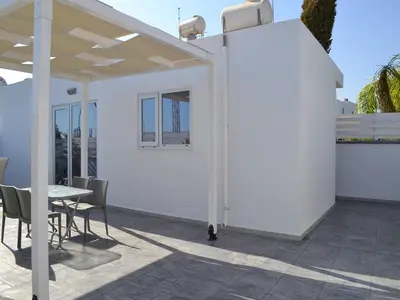 a white pergola on a patio with a table and chairs at Makronissos Beach Studio in Ayia Napa