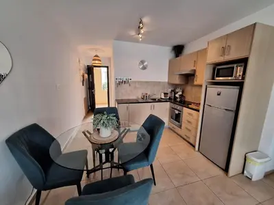 a kitchen with a glass table and blue chairs at Apartment Helena in Paralimni