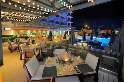 a restaurant with tables and chairs and a pool at Nestor Hotel in Ayia Napa