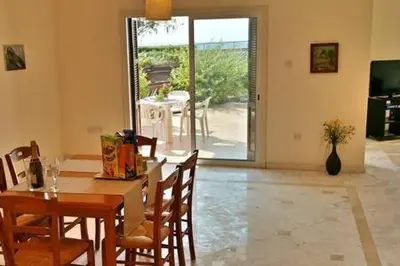 a dining room with a table and chairs and a door to a patio at Larnaka Beach House 3 in Larnaka