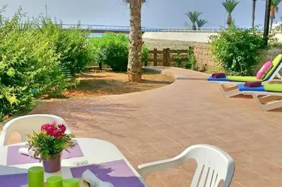 a patio with lounge chairs and a table with flowers at Larnaka Beach House 3 in Larnaka
