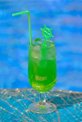 a drink sitting on a table next to a pool at Napa Prince Hotel Apts in Ayia Napa