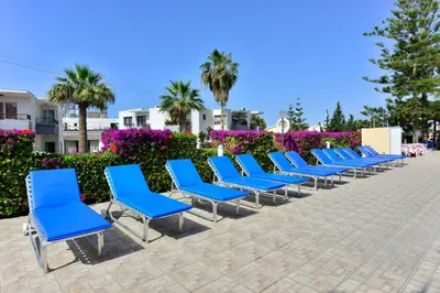 a row of blue chairs sitting on a sidewalk at Napa Prince Hotel Apts in Ayia Napa