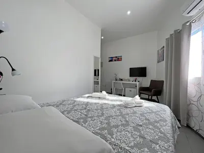 a white bedroom with a bed and a chair at Apollo Rooms by Albert's Apartment in Larnaka