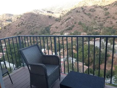 a balcony with a chair and a view of a mountain at Theoxenia in Kalopanayiotis