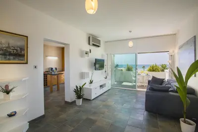 a living room with a couch and a television at Larnaca Sunshore Beachfront Suite in Voroklini