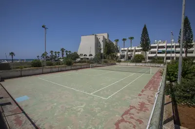 a tennis court in front of a building at Larnaca Sunshore Beachfront Suite in Voroklini