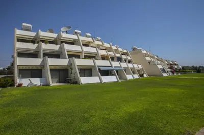 a building with a green lawn in front of it at Larnaca Sunshore Beachfront Suite in Voroklini