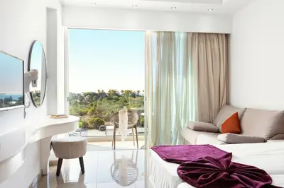 a hotel room with a couch and a mirror at Amethyst Napa Hotel & Spa in Ayia Napa