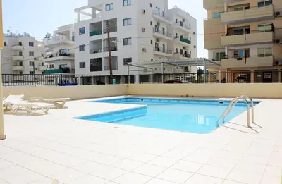 a swimming pool in front of a building at Makenzy Apartment in Larnaka