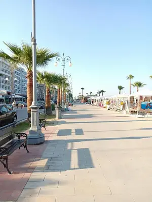 a sidewalk with benches and palm trees on a beach at Studio Apartment Near the Beach in Larnaka