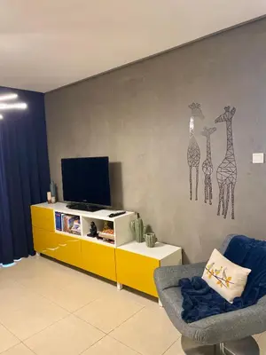 a living room with a tv and a yellow cabinet at Fat Cow Apartment 101 in Larnaka
