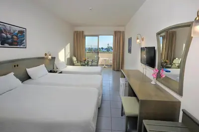 a hotel room with two beds and a television at Nissiana Hotel & Bungalows in Ayia Napa