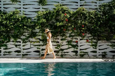 a woman in a hat walking by a swimming pool at Nissi Park Hotel in Ayia Napa