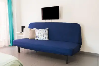 a blue couch sitting in a room with a tv at Mackenzie Blu Beach Studio in Larnaka