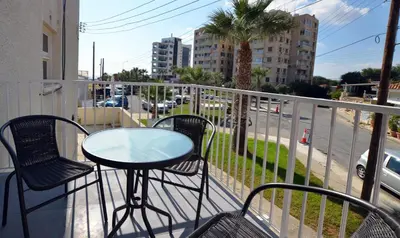a balcony with a table and chairs and a street at Mackenzie Blu Beach Studio in Larnaka