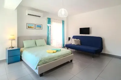 a bedroom with a bed and a blue couch at Mackenzie Blu Beach Studio in Larnaka