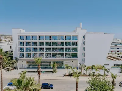 a large white building with palm trees in front of it at Seasons Hotel (Adults Only) in Ayia Napa