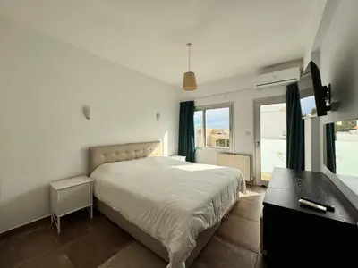 a bedroom with a bed and a desk and a window at Vega Apartments in Limassol