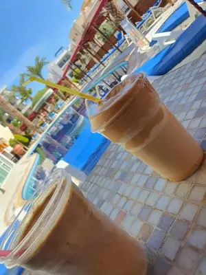a drink in a glass jar next to a pool at M. Moniatis Hotel in Limassol