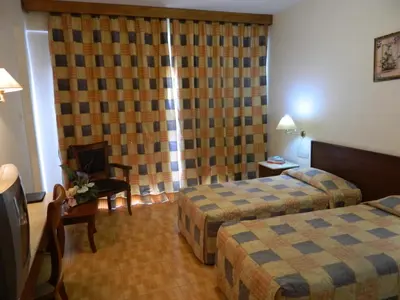 a hotel room with two beds and a television at M. Moniatis Hotel in Limassol