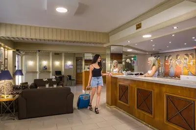 a woman with a suitcase standing at a counter in a salon at Christabelle Hotel Apartments in Ayia Napa