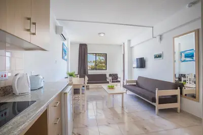 a kitchen and living room with a couch and a table at Christabelle Hotel Apartments in Ayia Napa