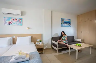 a woman sitting on a chair in a hotel room at Christabelle Hotel Apartments in Ayia Napa
