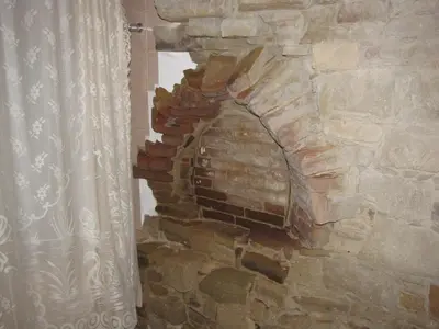 a stone wall with a fireplace in a room at Vasilopoulos House in Tochni