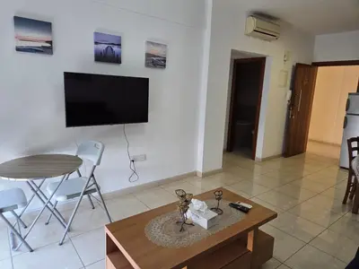 a living room with a table and a tv at One Bedroom aptm Larnaca in Larnaka