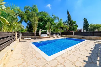a swimming pool in a backyard with a hammock and trees at Villa Greco Mare #5 in Paralimni