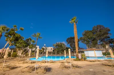 a resort swimming pool with chairs and a palm tree at Narcissos Waterpark Resort in Protaras