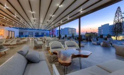 a rooftop lounge with white furniture and a view of the city at The Blue Ivy Hotel & Suites in Protaras