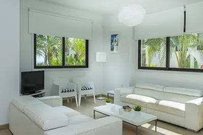 a living room with white couches and a tv at Protaras Holiday Villa Alexa in Protaras