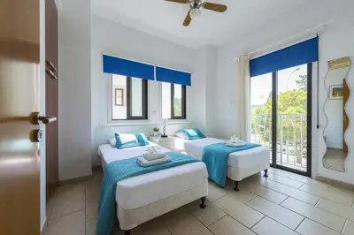 two beds in a room with two windows at Protaras Holiday Villa Alexa in Protaras