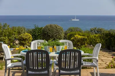 a table and chairs with the ocean in the background at Protaras Beachfront Sirina Lina Suite in Paralimni