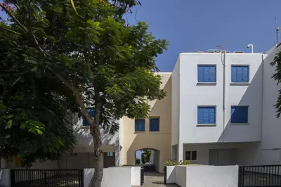 a white building with a tree in front of it at Protaras Beachfront Sirina Lina Suite in Paralimni