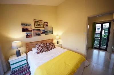 a bedroom with a bed with white sheets and a yellow blanket at Christos beach house in Larnaka